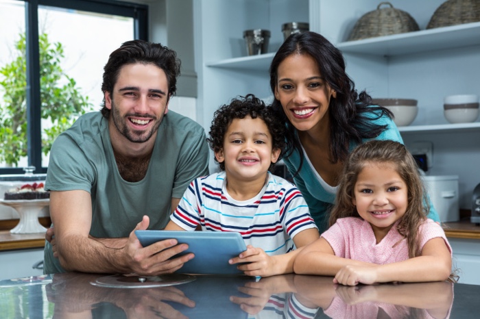 Young happy family of four smiling in kitchen